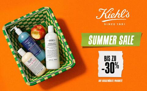 Kiehl's Summer Sale – Bis zu -30% auf eine Auswahl an Produkten, mit Creme de Corps, Facial Fuel und Amino Acid Conditioner in einem Picknickkorb auf orangem Hintergrund