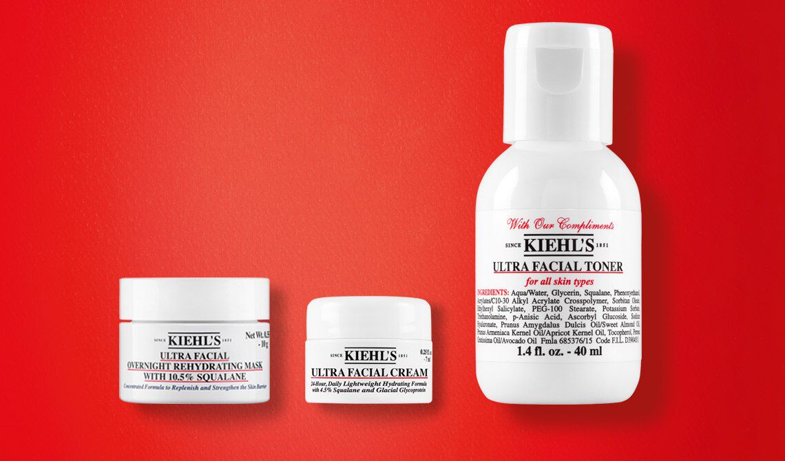 Kiehl's Mini-Produkt-Trio auf rotem Hintergrund: Ultra Facial Overnight Rehydrating Mask mit 10,5% Squalan, Ultra Facial Cream und Ultra Facial Toner fur alle Hauttypen