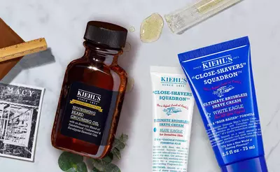 Braunem Flaschchen mit Bartol und zwei Rasiercremes von Kiehl's auf einem Tisch, umgeben von Pflegeprodukten.