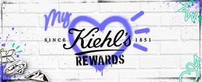Kiehls Rewards-Logo auf einer weißen Ziegelwand, umgeben von bunten grafischen Elementen und Herzmotiven.