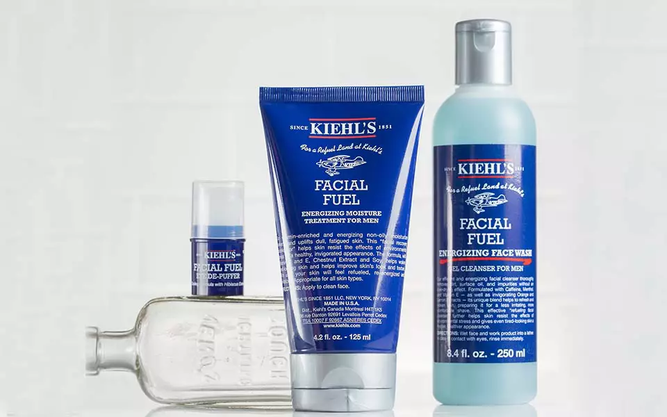Ein Banner mit Kiehl's Gesichtsprodukten, darunter eine Flasche, eine Tube und ein Tiegel, vor einem hellen, marmorierten Hintergrund.