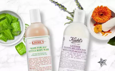 Zwei Kiehl's Korperpflegeprodukte: sanfte Korperwasche und Lavendel-Bad, umgeben von Aloe Vera und Blumen.