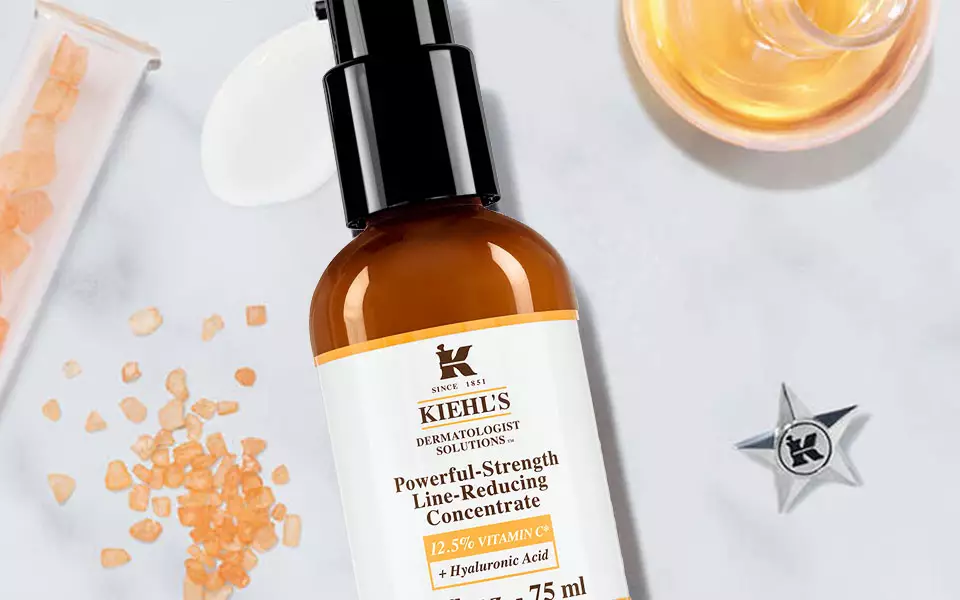 Alt-Text: Eine minimalistische Anordnung von Hautpflegeprodukten auf einer marmorierten Oberflache, einschließlich einer Flasche mit Serum und einer Flasche mit Feuchtigkeitscreme, umgeben von verschiedenen Inhaltsstoffen wie Kristallen und Olen.
