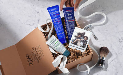 Ein Geschenkset mit Kiehl's Hautpflegeprodukten in einer Box, umgeben von Seidenpapier und einem Rasierer.