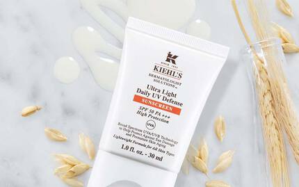 Alt-Text: Verschiedene Hautpflegeprodukte von Kiehl's auf einer marmorierten Oberflache, einschließlich einer Flasche und einer Tube, umgeben von naturlichen Zutaten.