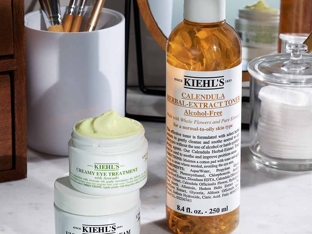 Kiehl's Produkte auf einem Waschtisch: Calendula Toner, Creamy Eye Treatment und ein weiteres Produkt, umgeben von Kosmetikzubehor.