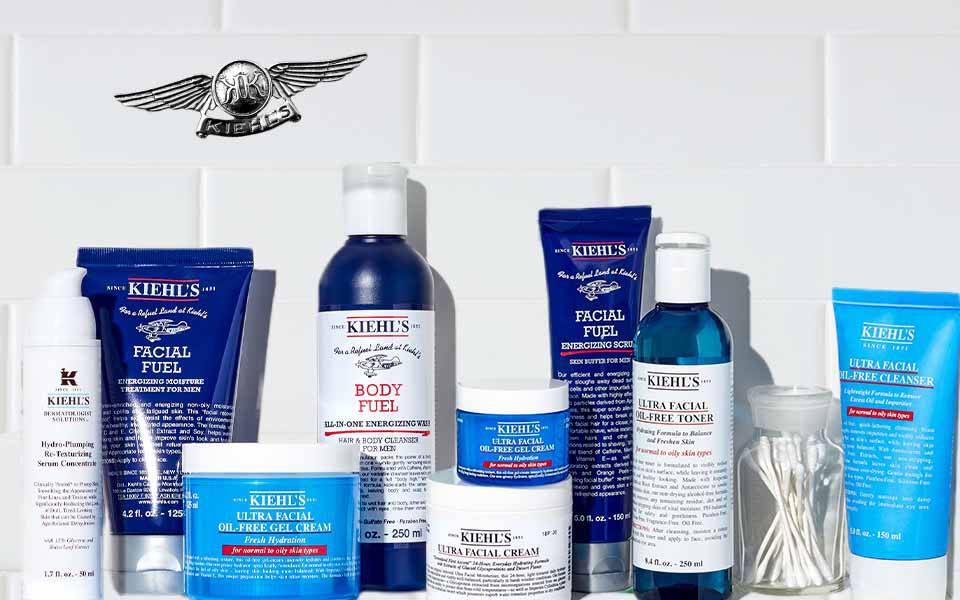 Eine Anordnung von verschiedenen Korperpflegeprodukten auf einem weißen Kachelhintergrund.