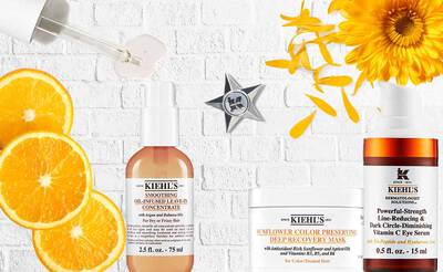 Alt-Text: Eine flache Layouteinstellung mit Kiehl's Hautpflegeprodukten, darunter ein Hautkonzentrat, eine Maske und ein Augenserum, umgeben von Orangenscheiben und gelben Bluten.