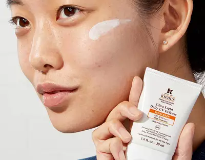 Frau mit Sonnencreme auf der Wange halt Uv Defense