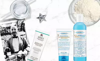 Kiehls Hautpflegeprodukte liegen auf einem Tisch, umgeben von alten Fotos und Krauterzubereitungen.