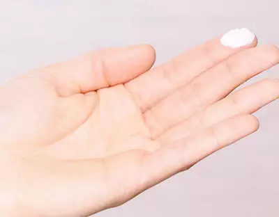 Hand mit Sonnencreme auf dem Finger