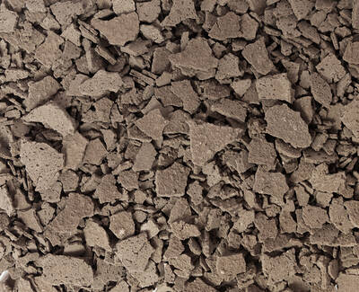 A close-up view of a textured surface covered in small, irregularly shaped brown fragments resembling crushed soil or rock.