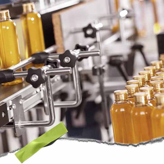 Eine automatisierte Abfullanlage mit klaren Flaschen, gefullt mit gelber Flussigkeit, und Metallklammern, die eine geschaftige Produktionsumgebung zeigt