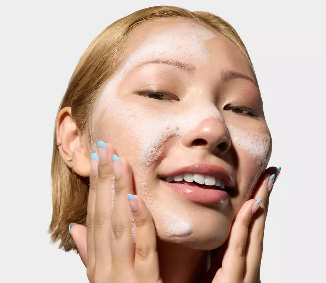 Flaschen mit Kiehl’s Hautpflegeprodukten mit Vitamin C vor einem Hintergrund aus Orangen und Orangenscheiben