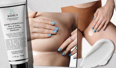 A tube of Kiehl's Over & Under Cream-to-Powder Deodorant is shown next to a close-up of a person applying the product under their arm. The hand has light blue nail polish and is gently smoothing the cream on the skin. A small amount of the cream is also displayed on a white surface.