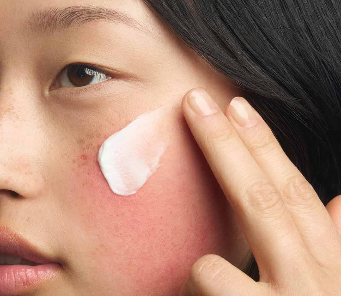 Action shot of the Kiehl's Ultra Facial Barrier-Hydrating Cleanser in use. The image shows the cream-to-foam formula creating a rich lather as it is massaged into the skin, demonstrating a gentle and refreshing cleansing experience.