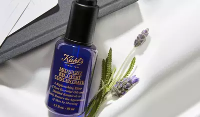 Bildcollage bestehend aus dem Midnight Recovery Concentrate mit Blumen arrangiert und auf einem Tisch mit Tischdecke liegend.
